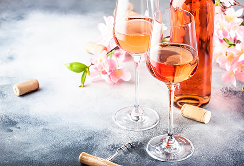 Zwei Weingläser mit Rosé auf einem grauen Tisch, eine Flasche Rosé im Hintergrund