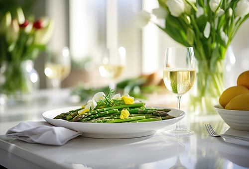 Ein Teller mit grünem Spargel und ein Glas Weißwein auf einem Tisch