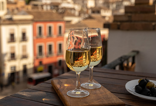 Zwei Gläser mit Sherry auf einem Tisch auf einem Balkon mit Ausblick über eine Stadt