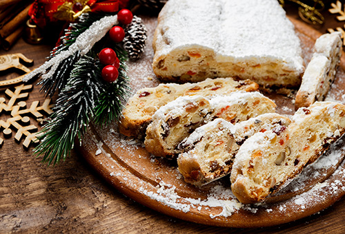 Dresdner Stollen, angeschnitten, auf einem Holzbrett auf einem weihnachtlich dekorierten Tisch