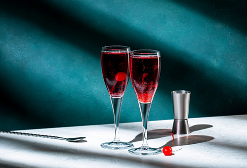 Zwei Gläser mit Kir Royal auf einem Tisch von einer blauen Wand