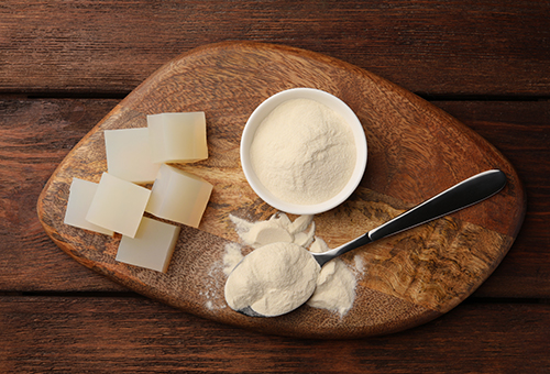 Vegetarisches Geliermittel - Agar Agar als Pulver und Gelierwürfel angerichtet auf einem Holzbrett