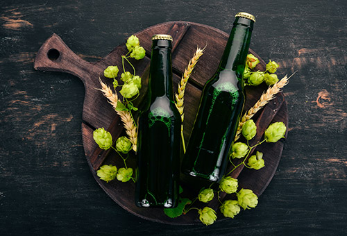 zwei Flaschen Bier auf einem Holzbrett mit Hopfen dekoriert