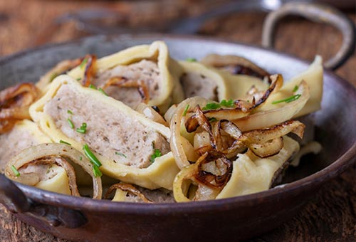 In Scheiben geschnittene Maultaschen angebraten mit Zwiebeln in einer Gusspfanne