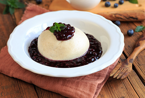 Dampfnudeln mit Vanillesoße und Kompott auf Teller