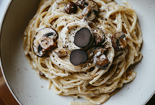 Pasta mit Sauce und Trüffelstücken versehen